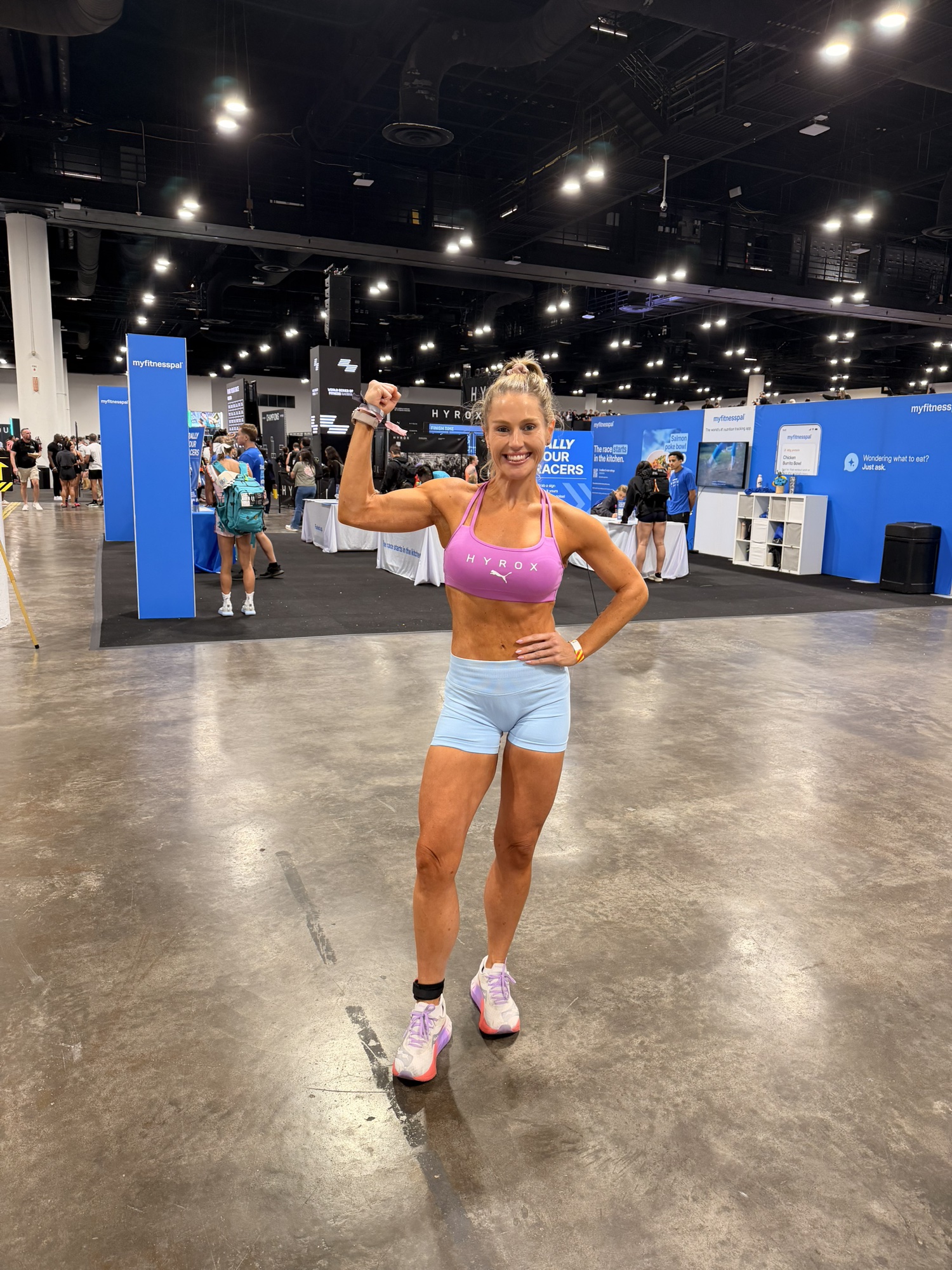Gen flexing and smiling at a Hyrox event, strong and joyful